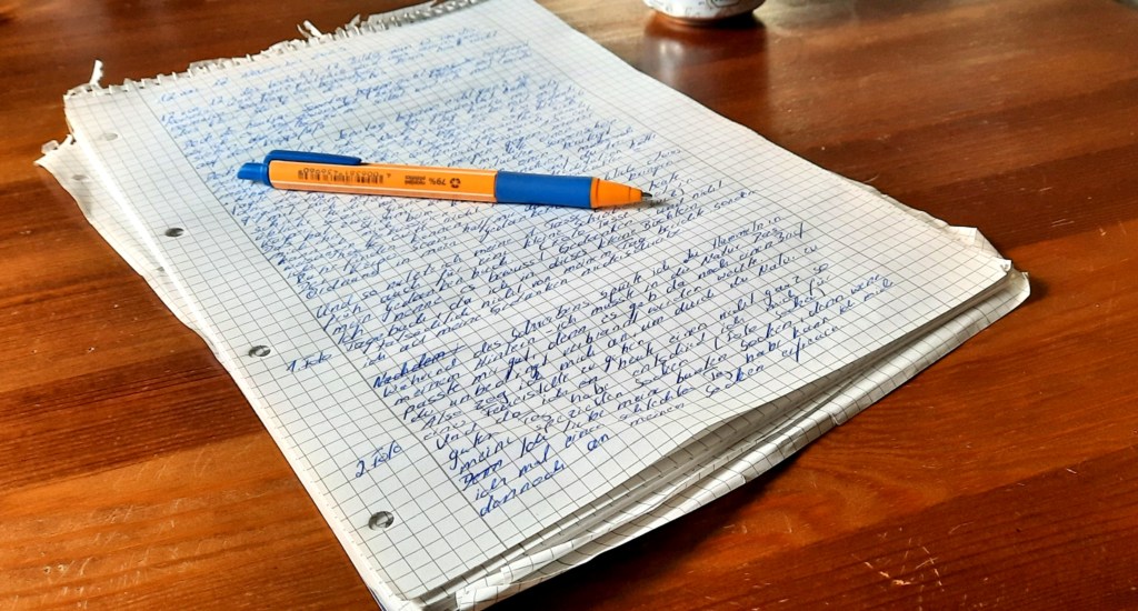 Ein vollgeschriebener Collegeblock auf einem braunen Tisch