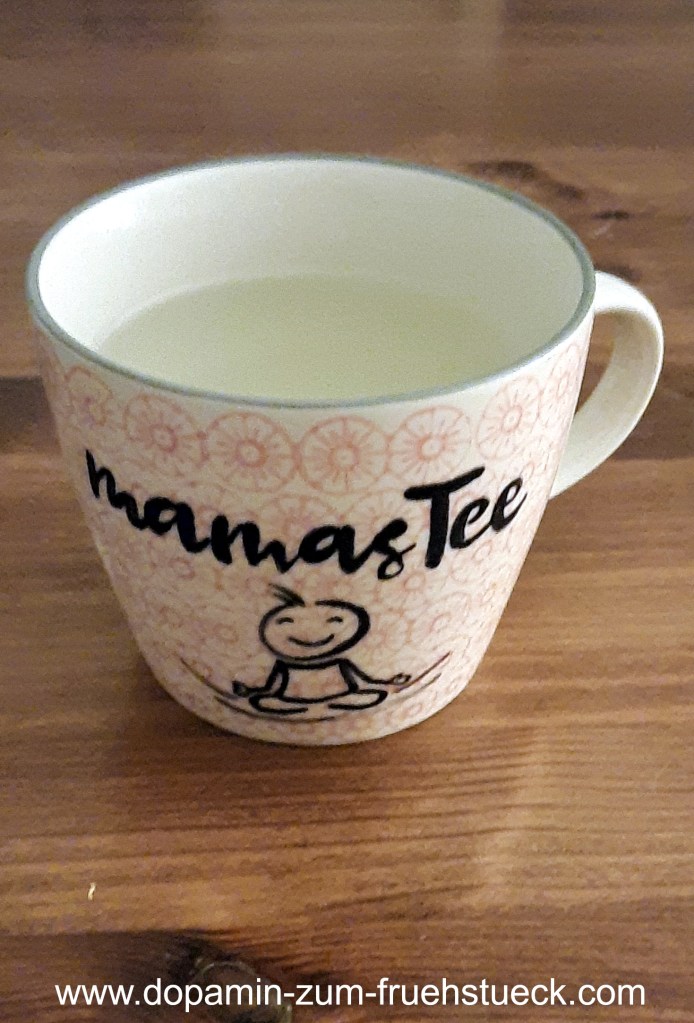 Eine helle Tasse mit roten Blumen und einem Strichmännchen in Meditationshaltung