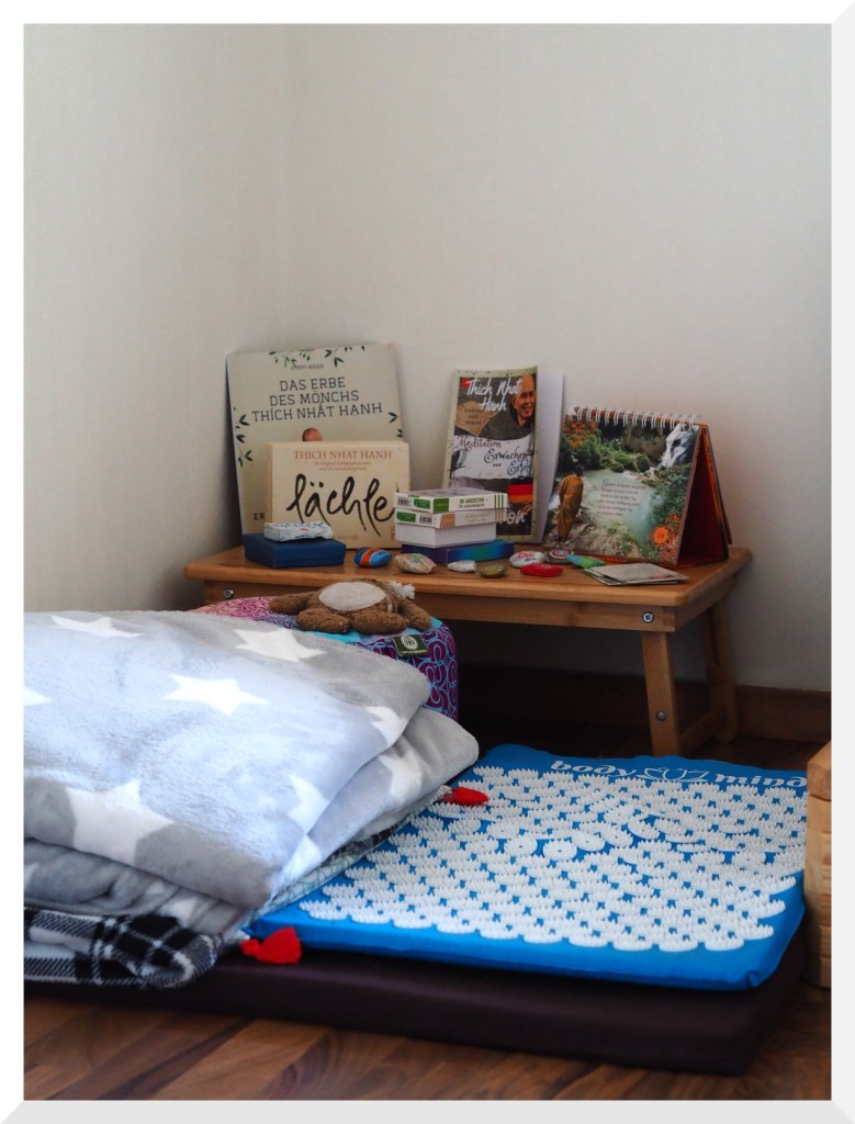 Meditationsecke. Man erkennt ein Meditationskissen, eine Shakti-Matte und zwei Wolldecken.