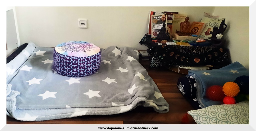 Meditationsecke- eine Decke, die auf dem Boden liegt, darauf ein Meditationskissen. Neben der Decke steht ein kleiner Altar mit Büchern und einer Statue von Thich Nhat Hanh