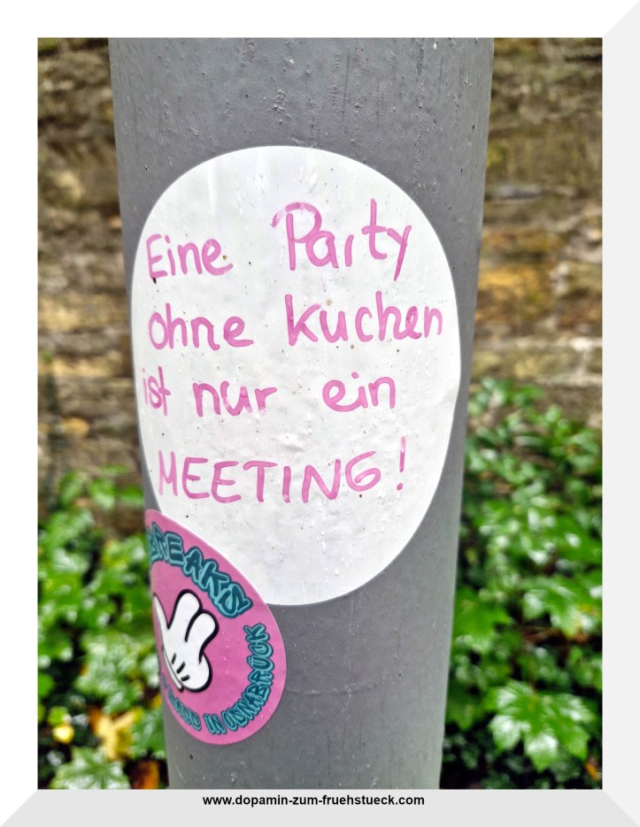 Ein Aufkleber an einer Straßenlaterne, auf dem Steht: "Eine Party ohne Kuchen ist nur ein Meeting"