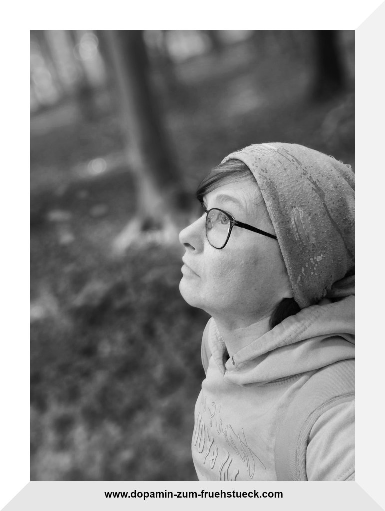 Schwarz weiß Foto einer Frau mit Brille und Mütze, die nach oben schaut.