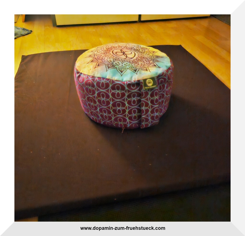 Ein lilafarbenes Meditationskissen liegt auf einer braunen Meditationsmatte