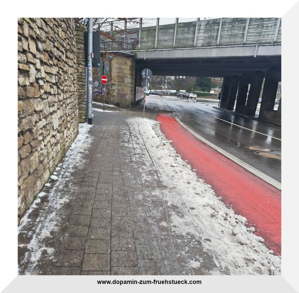Eine Straße, die durch eine Brücke entlang läuft. Die Starße ist von Schnee geräumt- die Gehwege sind vereist