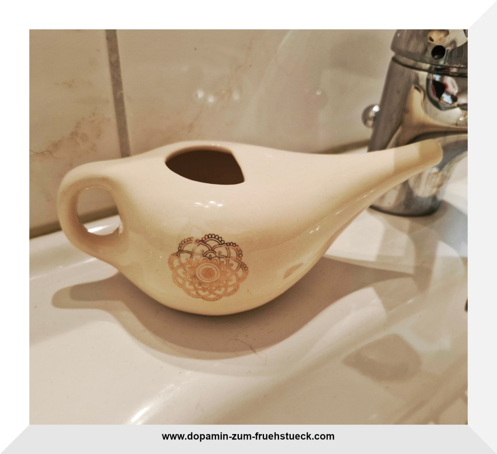 Ein weißes Nasenduschkännchen auf einem Waschbecken