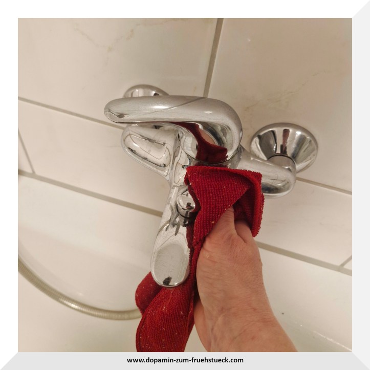 Eine Mischbatterie die mit einem Lappen gereinigt wird.