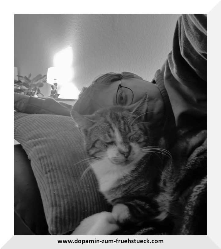 Schwarz weiß Foto von einer Frau, die auf einem Sofa liegt und vor ihr liegt eine Katze