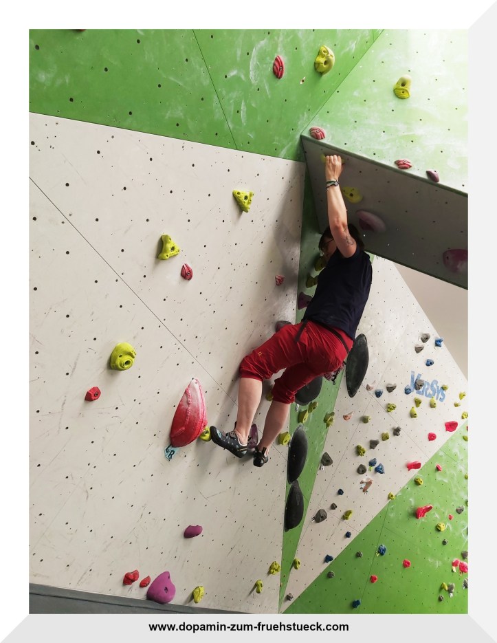 Eine Frau, die in einer Boulderhalle klettert